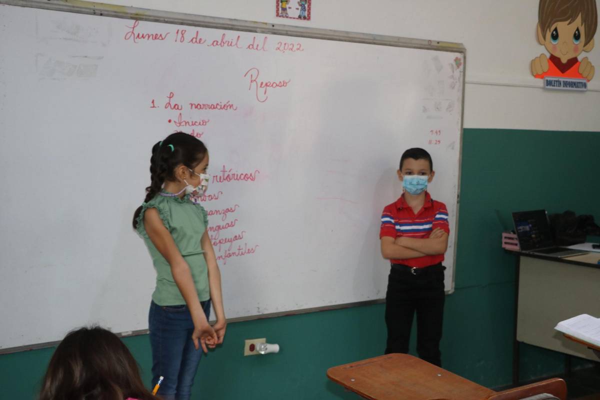 Dos escolares realizan una presentación durante el regreso a clases.