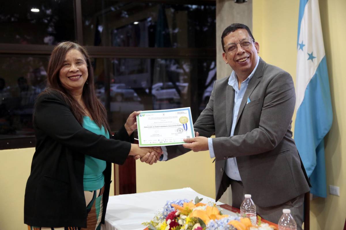 El vicerrector administrativo de la UPNFM, José Darío Cruz, hace entrega de su diploma a una de las graduadas.