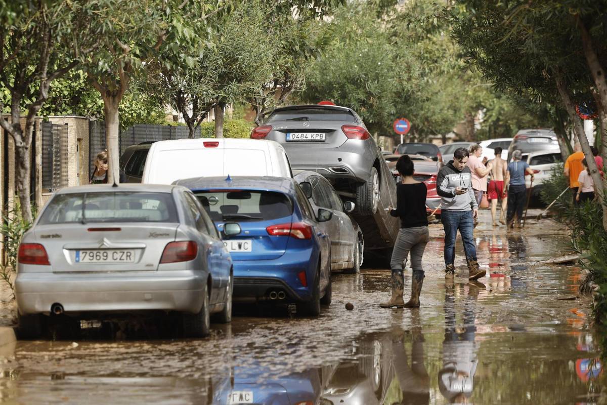 Varias personas junto a vehículos dañados por las intensas lluvias de la fuerte dana que afecta especialmente el sur y el este de la península ibérica, este miércoles en Picaña (Valencia).