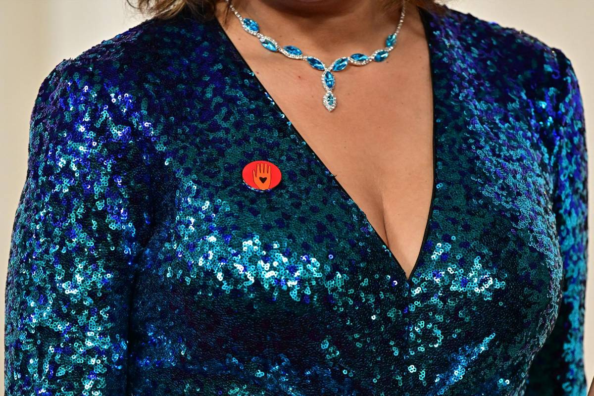 El broche muestra una mano naranja con un corazón negro.Los protagonistas de “Anatomía de una caída”, los franceses Swann Arlaud y Milo Machado-Graner, llevaban prendedores con la bandera palestina.