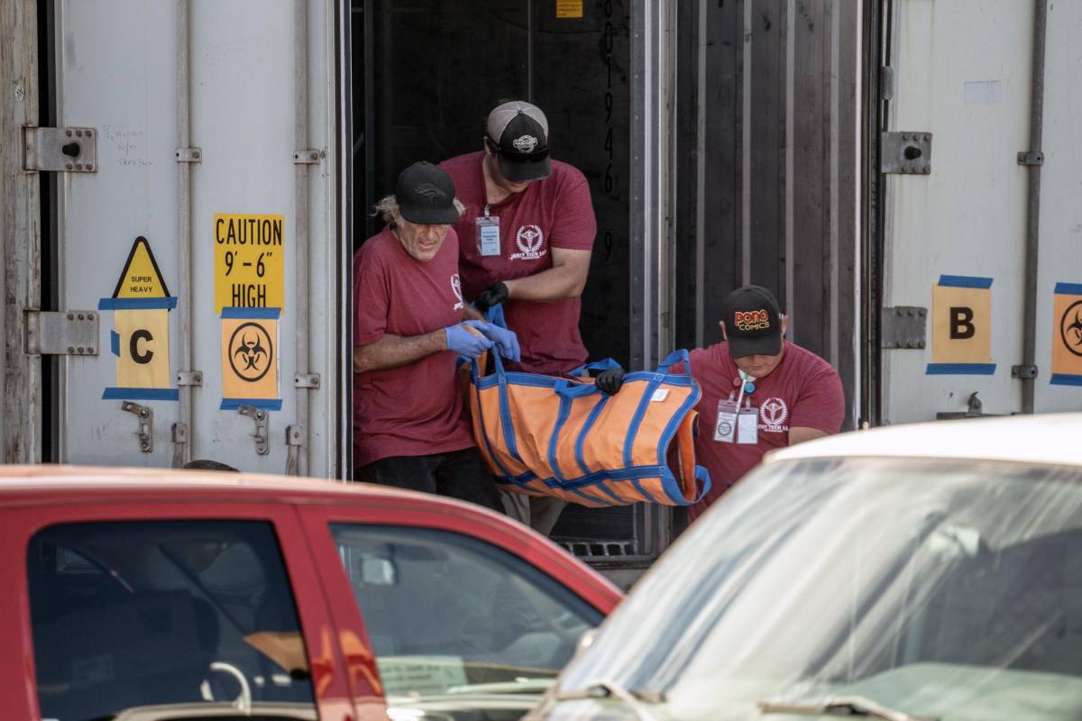 Los trabajadores de la morgue sacan el cuerpo de un residente que murió en el incendio forestal de la semana pasada de un remolque refrigerado en Wailuku, en la isla hawaiana de Maui.