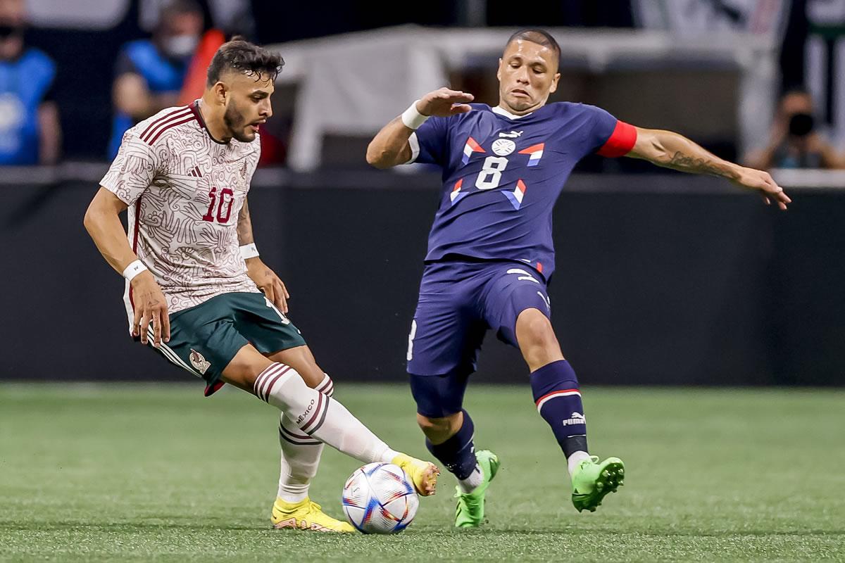 Alexis Vega de México conduce el balón ante la marca del paraguayo Richard Ortiz.