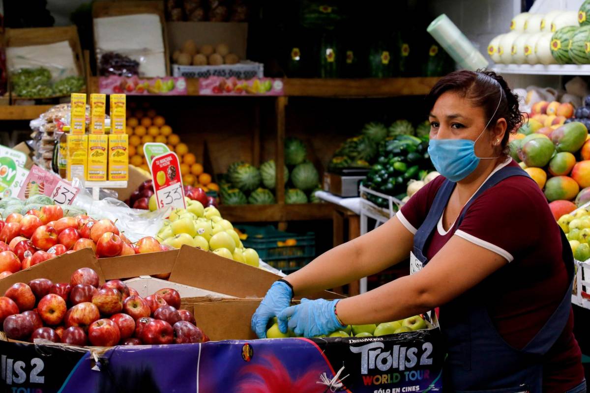 Una mujer vende frutas y verduras en un mercado.