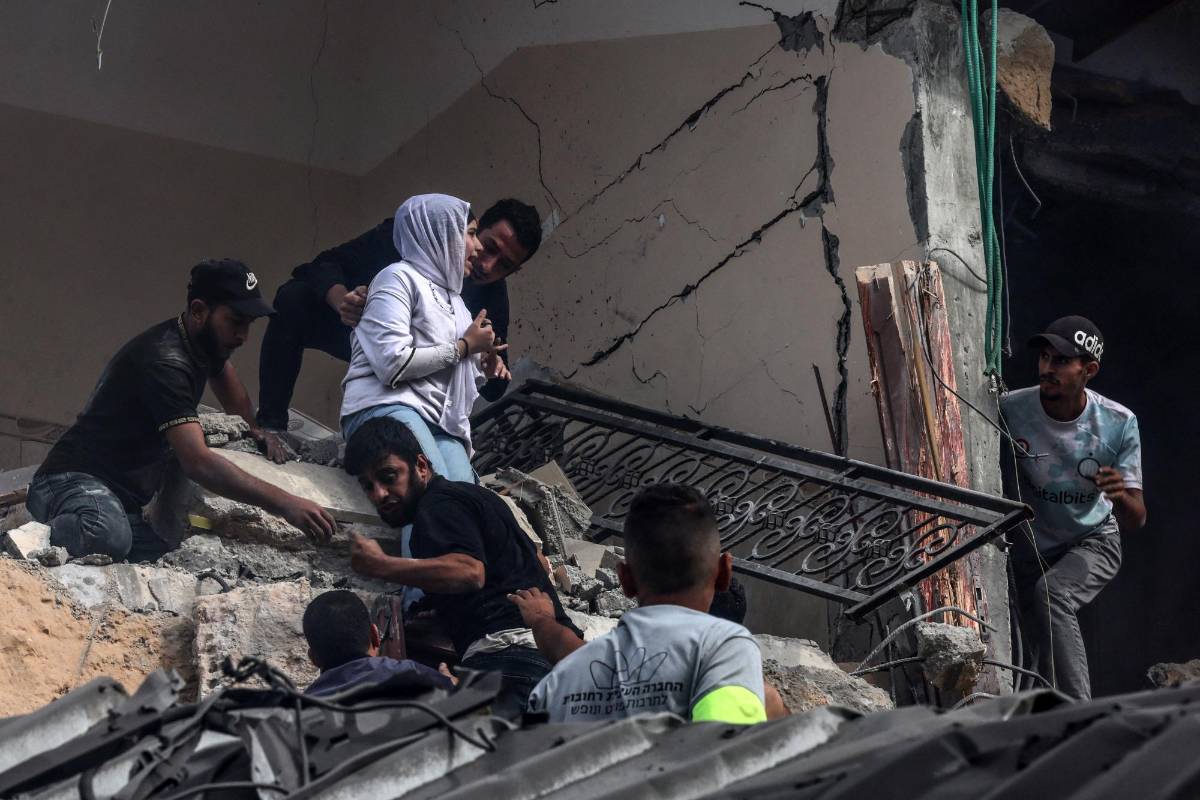 A woman is helped down from a building destroyed during Israeli bombing on Rafah in the southern Gaza Strip, on November 11, 2023, as battles between Israel and the Palestinian Hamas movement continue. (Photo by SAID KHATIB / AFP)