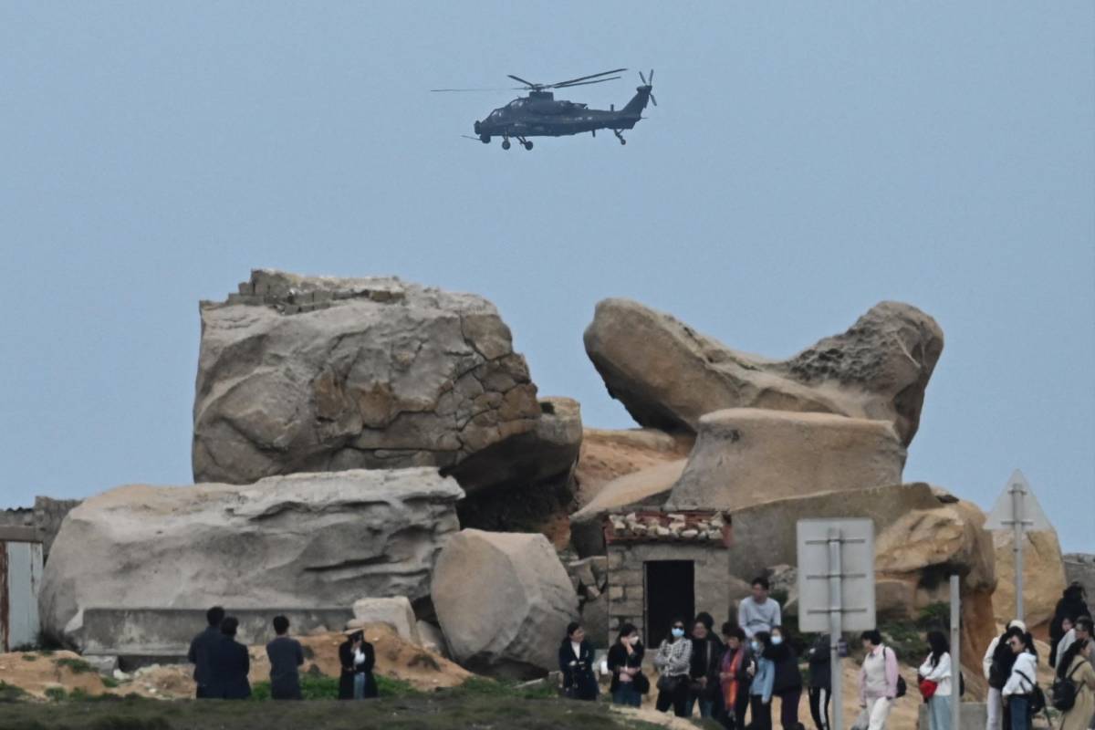 Turistas observan un helicóptero militar chino que sobrevuela el sur de Taiwán.