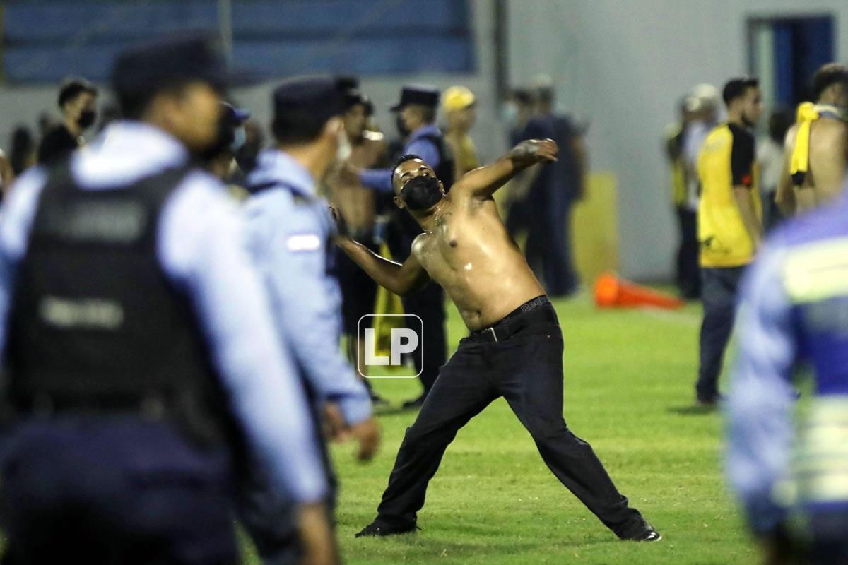 Este aficionado lanzando objetos durante una invasión de hinchas al campo de juego del estadio Morazán.