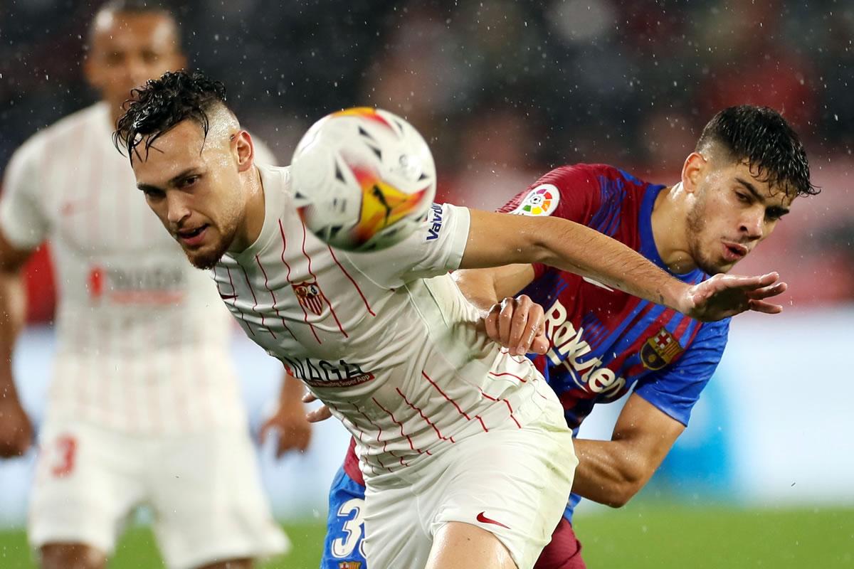 El delantero del Sevilla, Lucas Ocampos, pelea un balón con Abdessamad Ezzalzouli, del FC Barcelona.