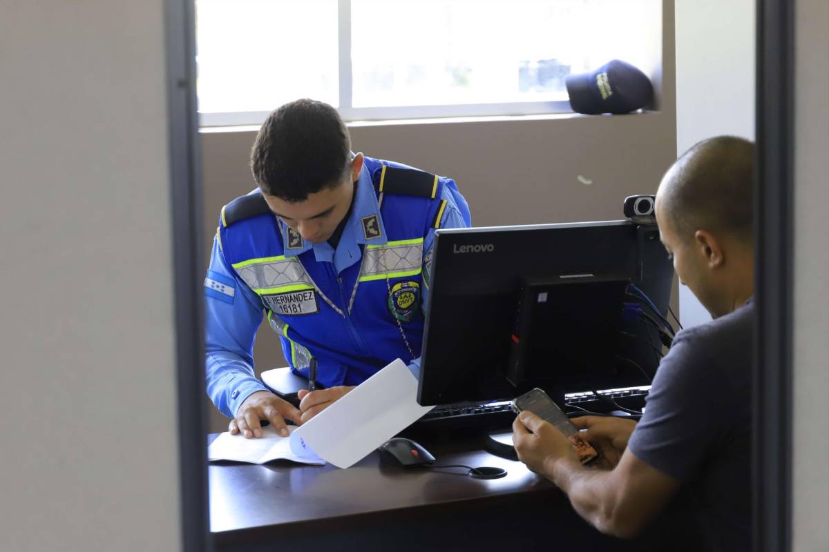Un agente policial revisa los documentos para posteriormente tomarle la fotografía al conductor que solicita la licencia de conducir.