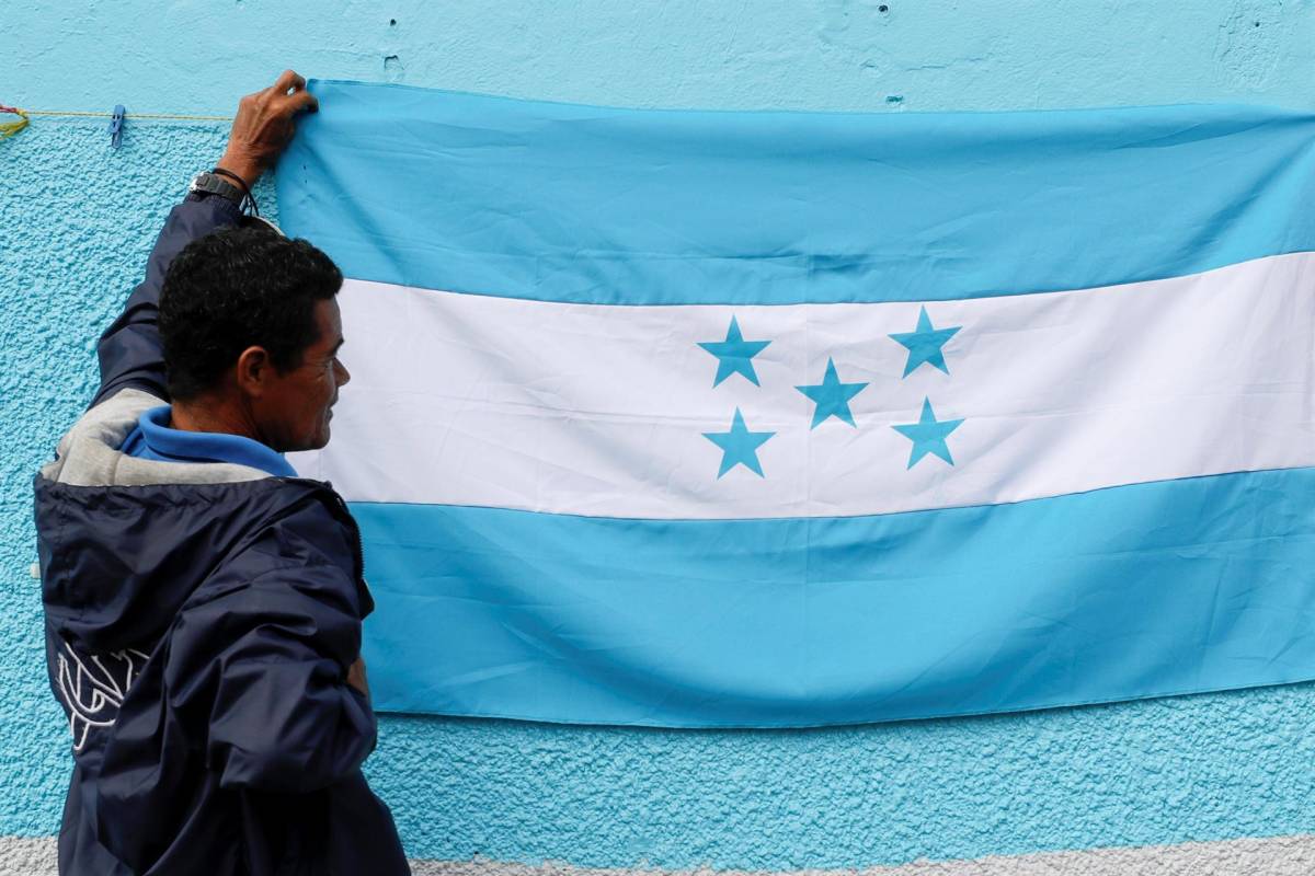 Un joven hondureño sostiene una bandera azul turquesa a inmediaciones del estadio Nacional Tiburcio Carías Andino, sede de la investidura.