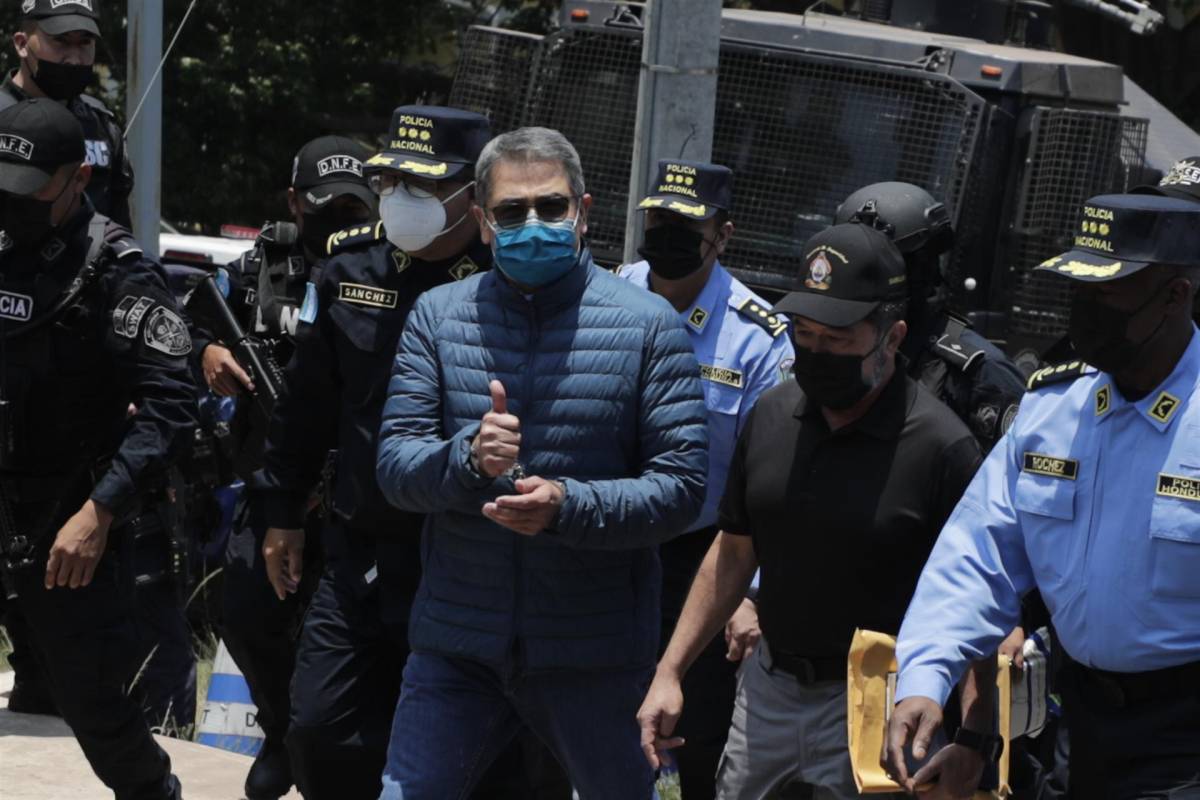 Juan Orlando Hernández, durante su traslado, saludó a medios de comunicación momentos antes de abordar un helicóptero, donde también lo acompañaba el ministro de Seguridad, Ramón Sabillón. Fotografía: EFE