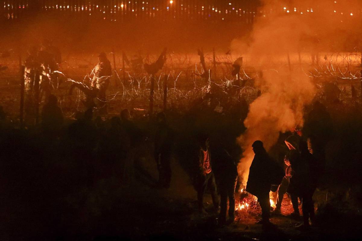 Migrantes se reúnen junto a una fogata en las orillas del Río Bravo a la espera de cruzar hacia territorio estadounidense.