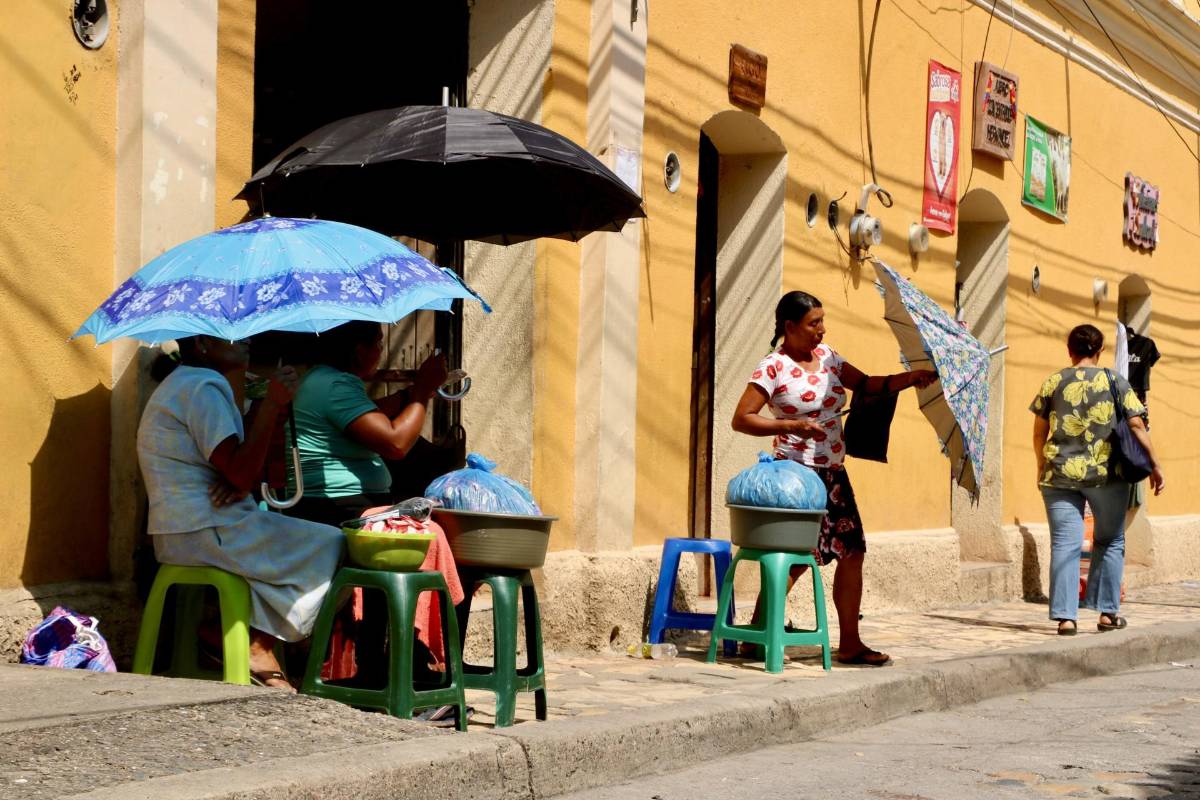 Mujeres se cubren de los ardientes rayos del sol en el centro histórico de Copán Ruinas.