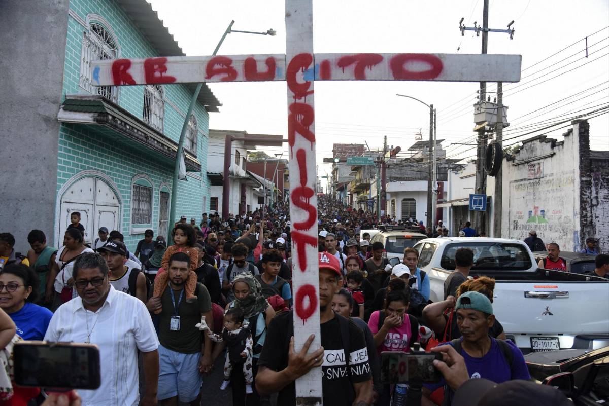 Un migrante hondureño carga la enorme cruz del viacrucis.