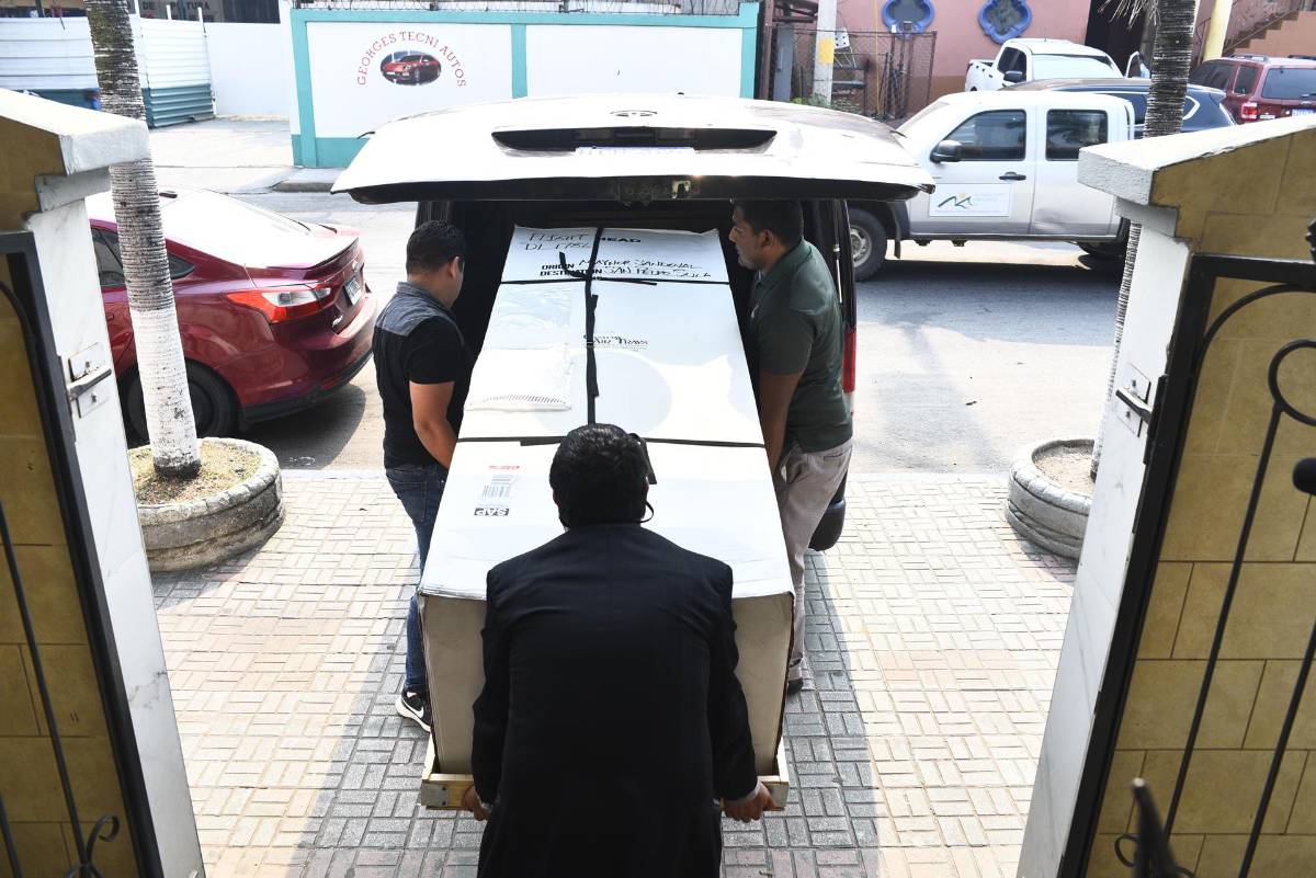 Trabajadores cargan el féretro con el cuerpo del hondureño Maynor Suazo.