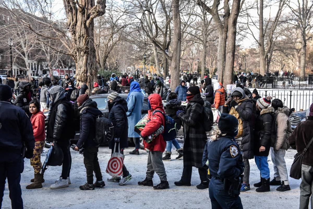 Migrantes sin hogar esperan donaciones de alimentos y ropa en Nueva York bajo extremas temperaturas.