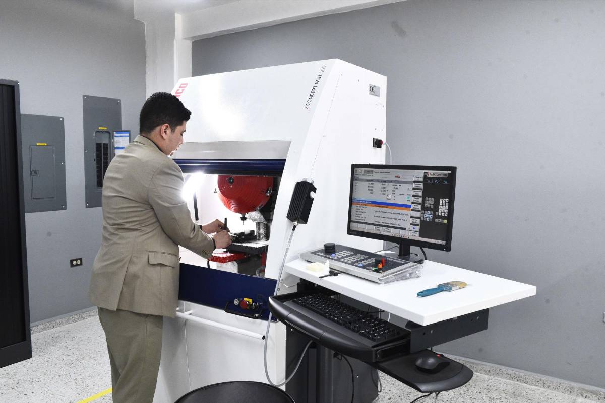 Un joven manipula una máquina para la creación de piezas con asistencia computarizada.