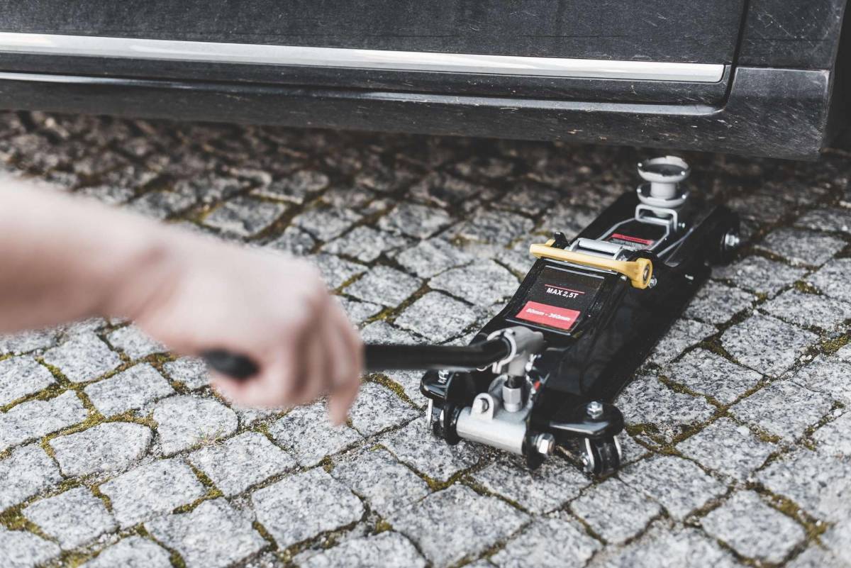 4) LEVANTA EL AUTO CON EL GATO HIDRÁULICO: Coloca el gato hidráulico debajo del carro (cerca de la llanta desinflada). Ahora, acciónalo y empieza a despegar el auto del suelo. ¡Recuerda! El gato va debajo del chasis, no de la carrocería.