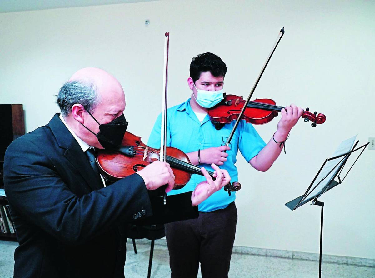 Jorge Banegas junto con un estudiante de la institución durante una práctica de violín.