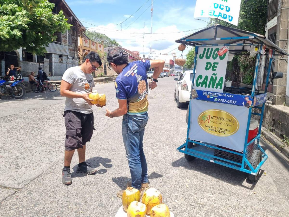 Álex atiendo a un joven cliente a un costado de la catedral en La Ceiba.