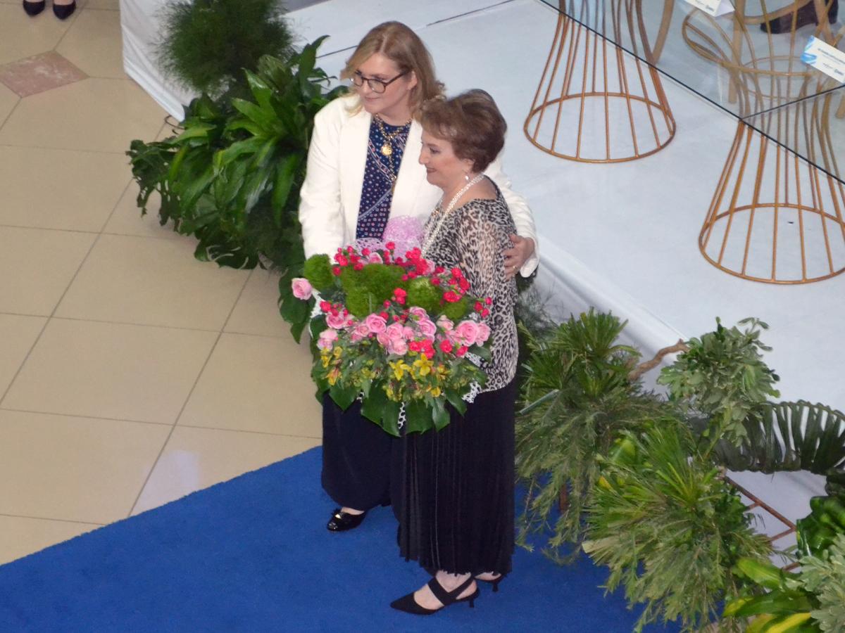 La distinguida dama María Elena Marcos, esposa de Emín Abufele, recibió un arreglo de flores de manos de la Presidenta Ejecutiva de Banpaís, María del Rosario Selman-Housein.