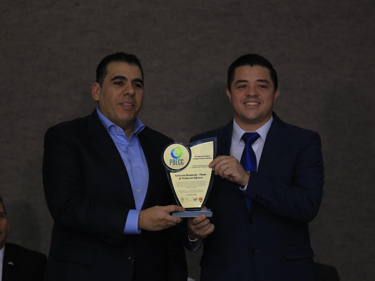 Mario Faraj, presidente de la junta directiva del CNP+LH, entrega el reconocimiento ambiental a Denis Banegas, director de la planta de Refrescos de Cervecería Hondureña.