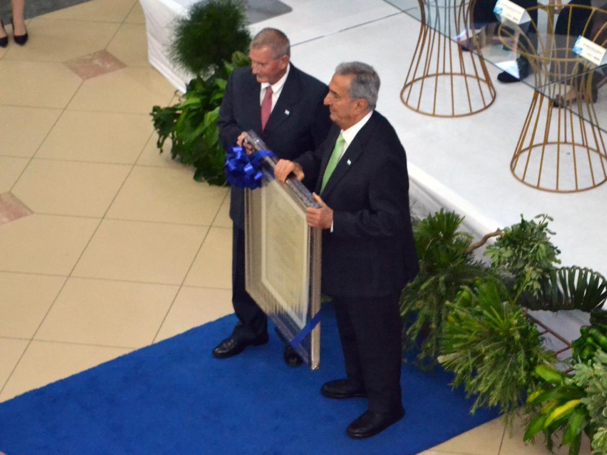 El Presidente de la Junta Directiva de Banpaís, Ramiro Castillo Arévalo, entregó el pergamino que lo acredita como Abanderado 2024 al empresario Emín Abufele.