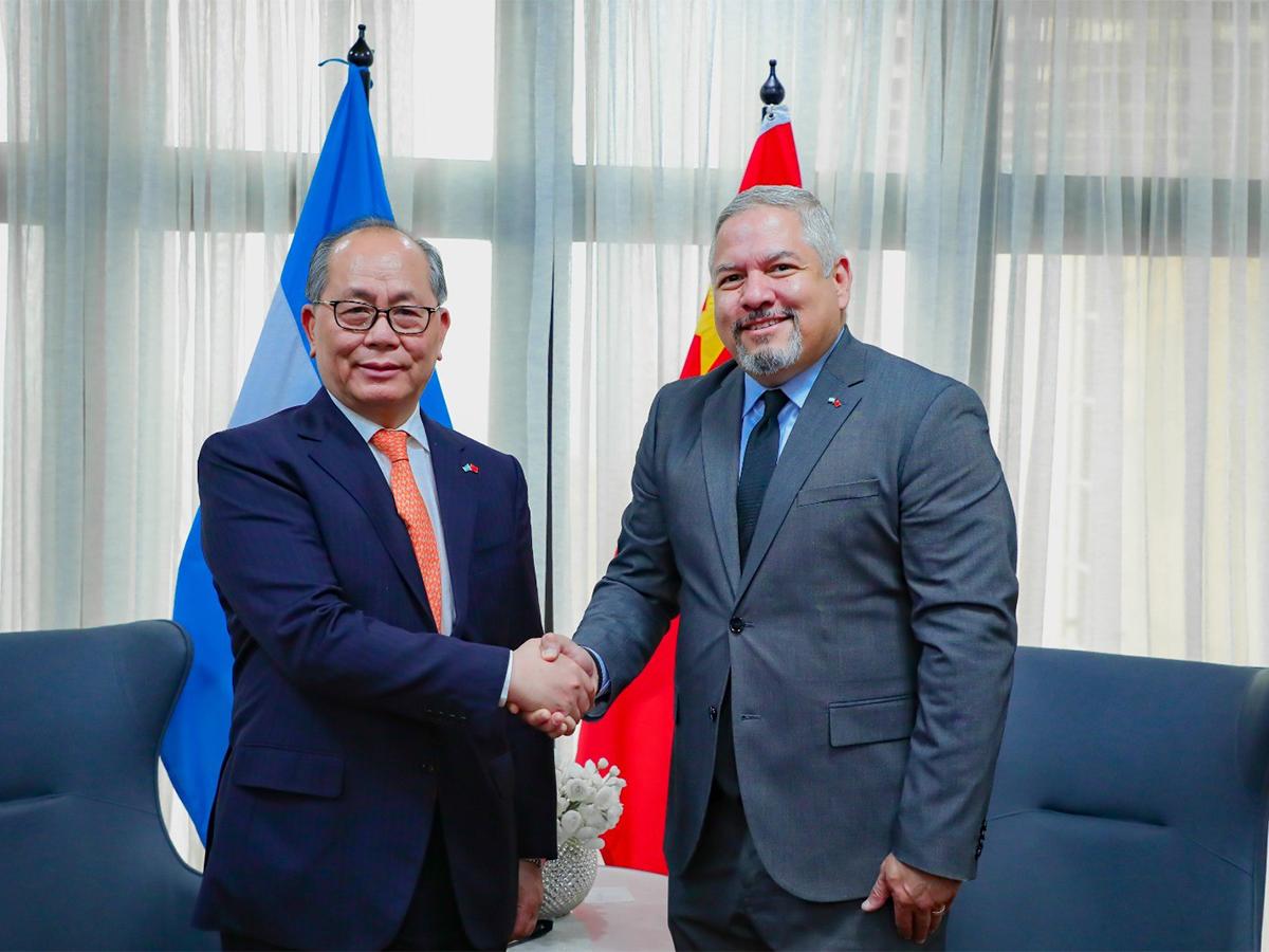 Secretario de Relaciones Exteriores y Cooperación Internacional, Eduardo Enrique Reina García, estrecha la mano con un representante chino.