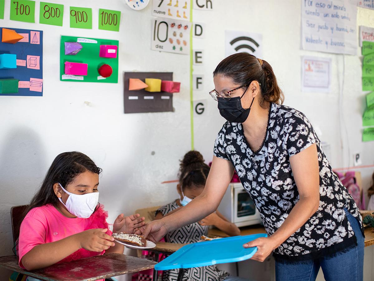 <i>Maestros y voluntarios preparando alimentos nutritivos para los estudiantes, contribuyendo a su salud y rendimiento académico.</i>