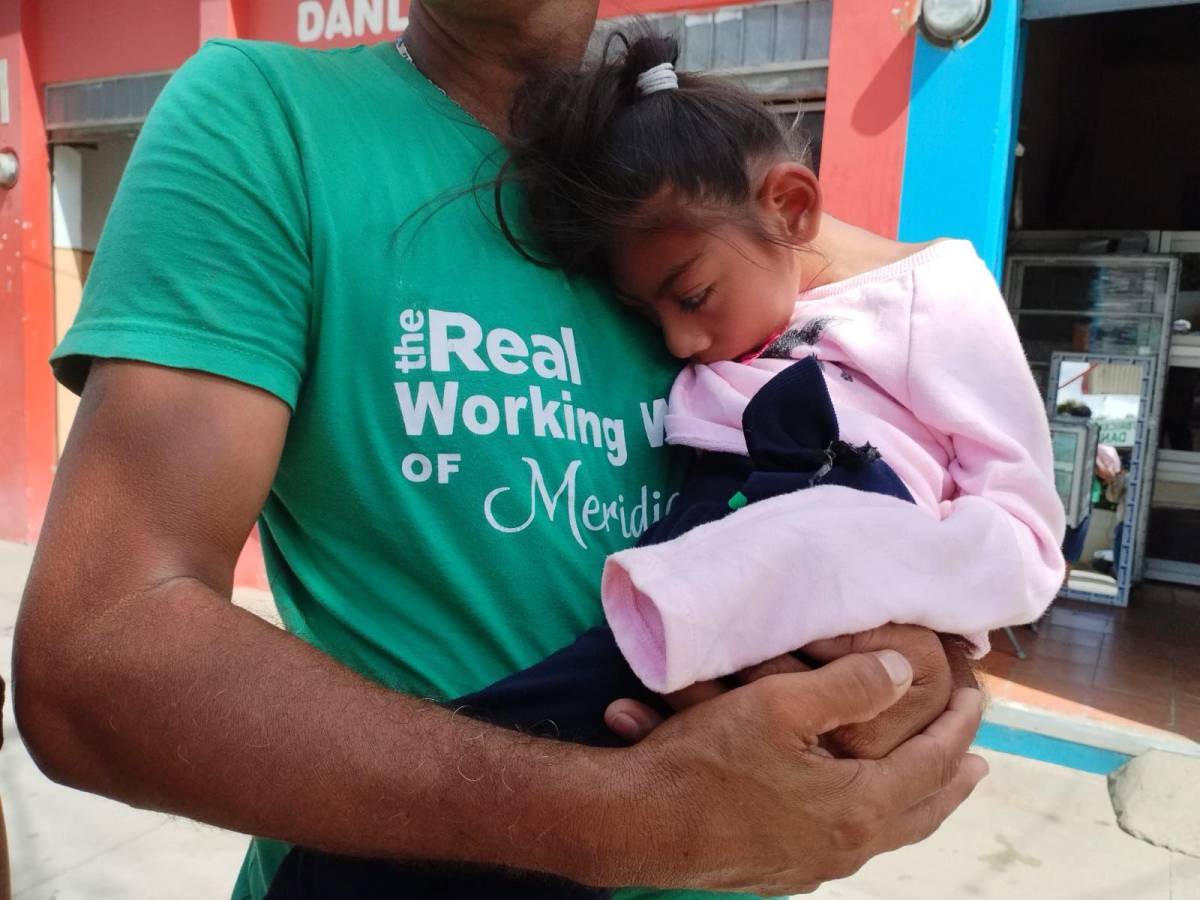Eduardo Ramón Macho carga en brazos a su hija con capacidades especiales.