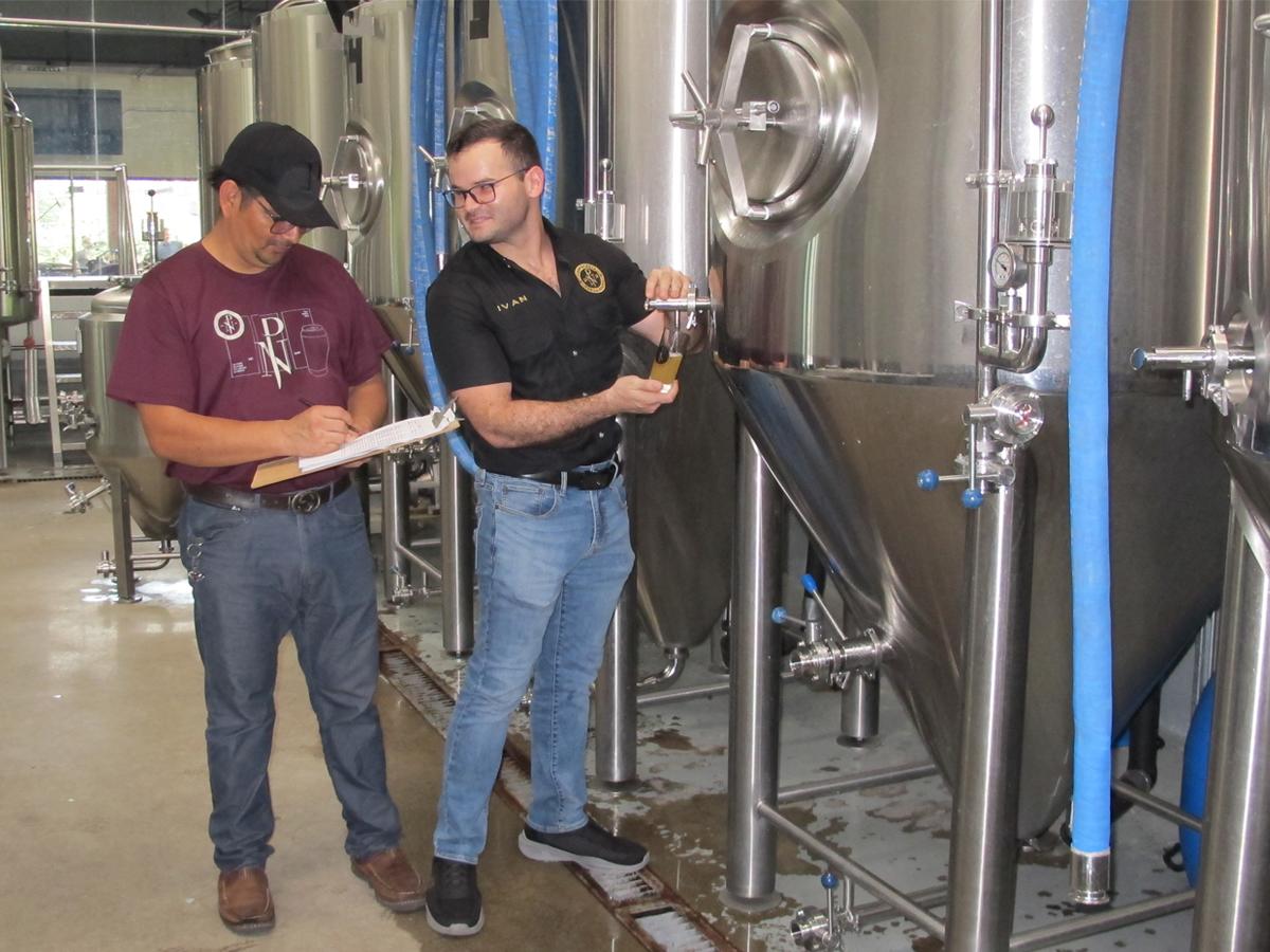 Iván Wolozny junto José María Gonzales, asistente cervecero, mientras realizan control de calidad en los fermentadores.