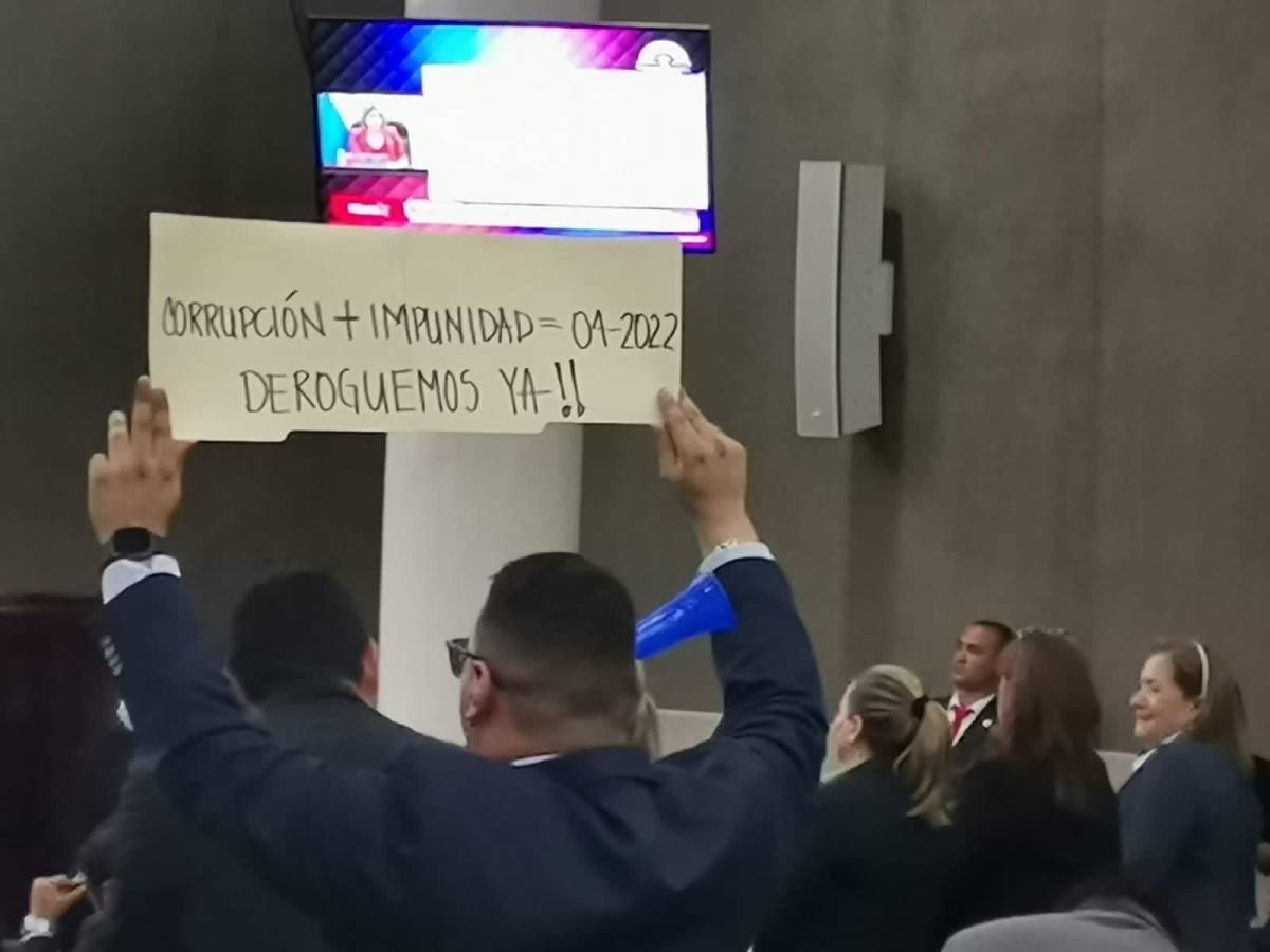 Diputado nacionalista sostiene una pancarta contra el pacto de impunidad.