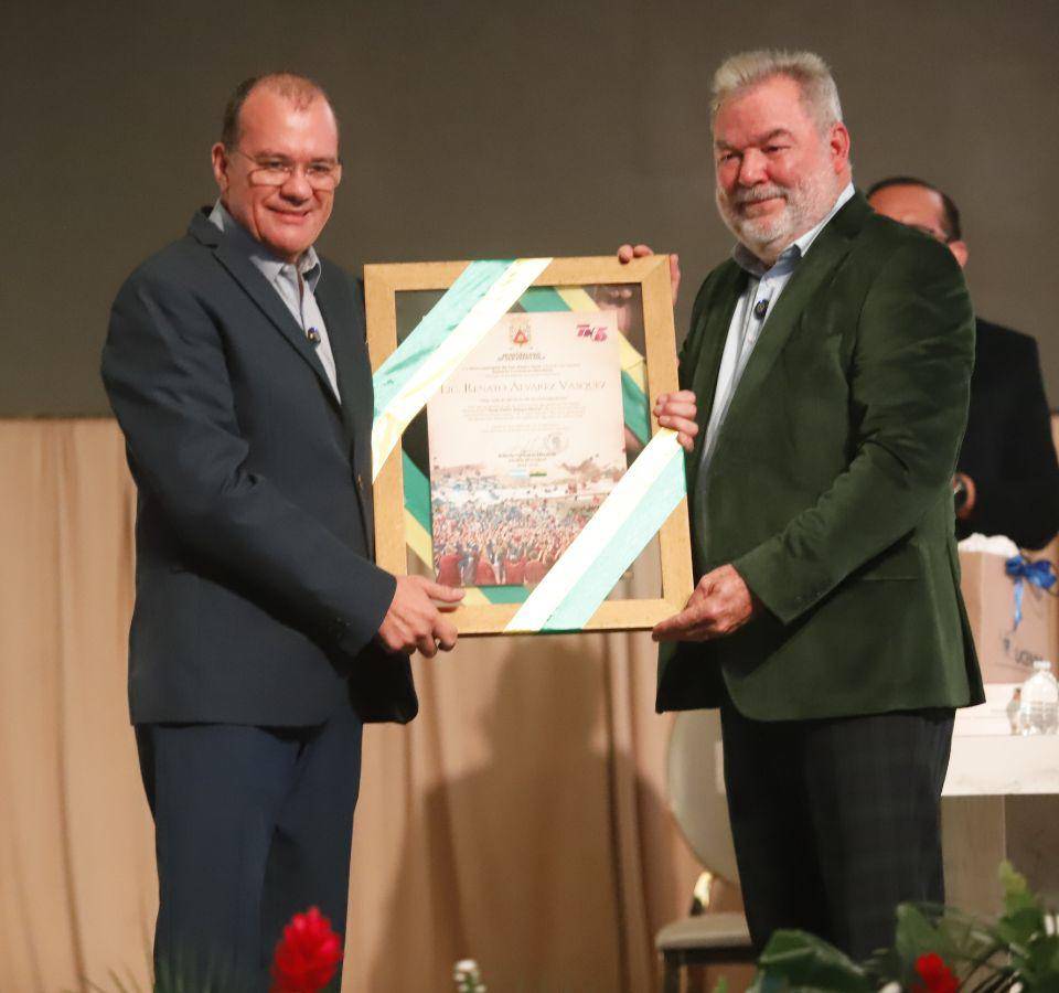 El periodista Renato Álvarez recibe un reconocimiento como padrino de la promoción de manos del alcalde Roberto Contreras.