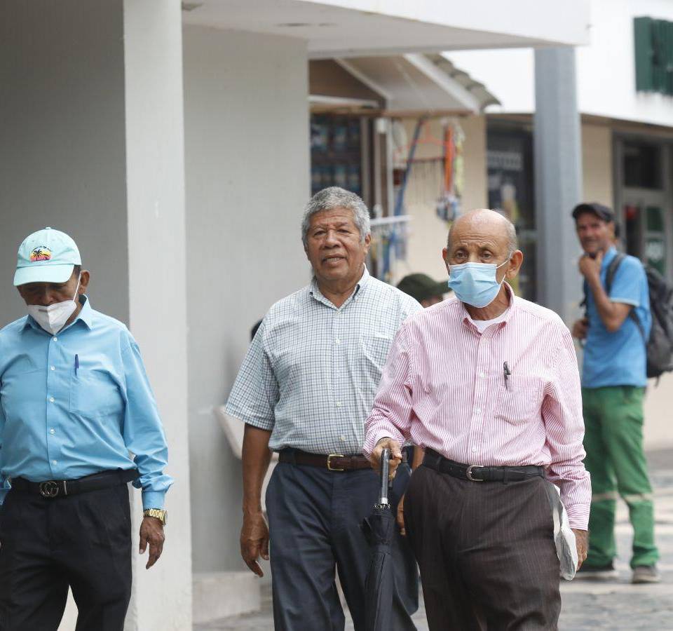 Un grupo de hombres caminan por el parque central de San Pedro Sula.
