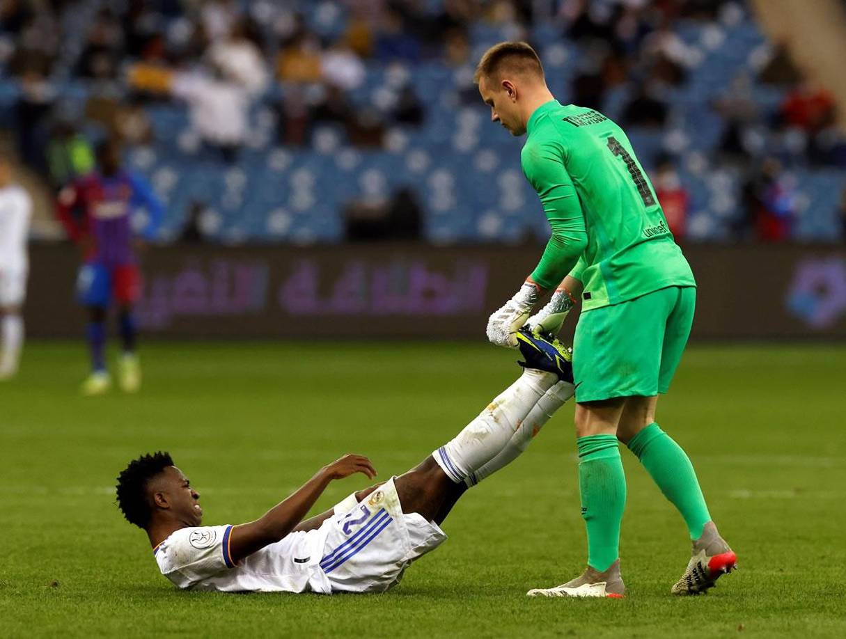 Vinicius Jr., ayudado por el guardameta alemán del FC Barcelona, Marc-André ter Stegen.
