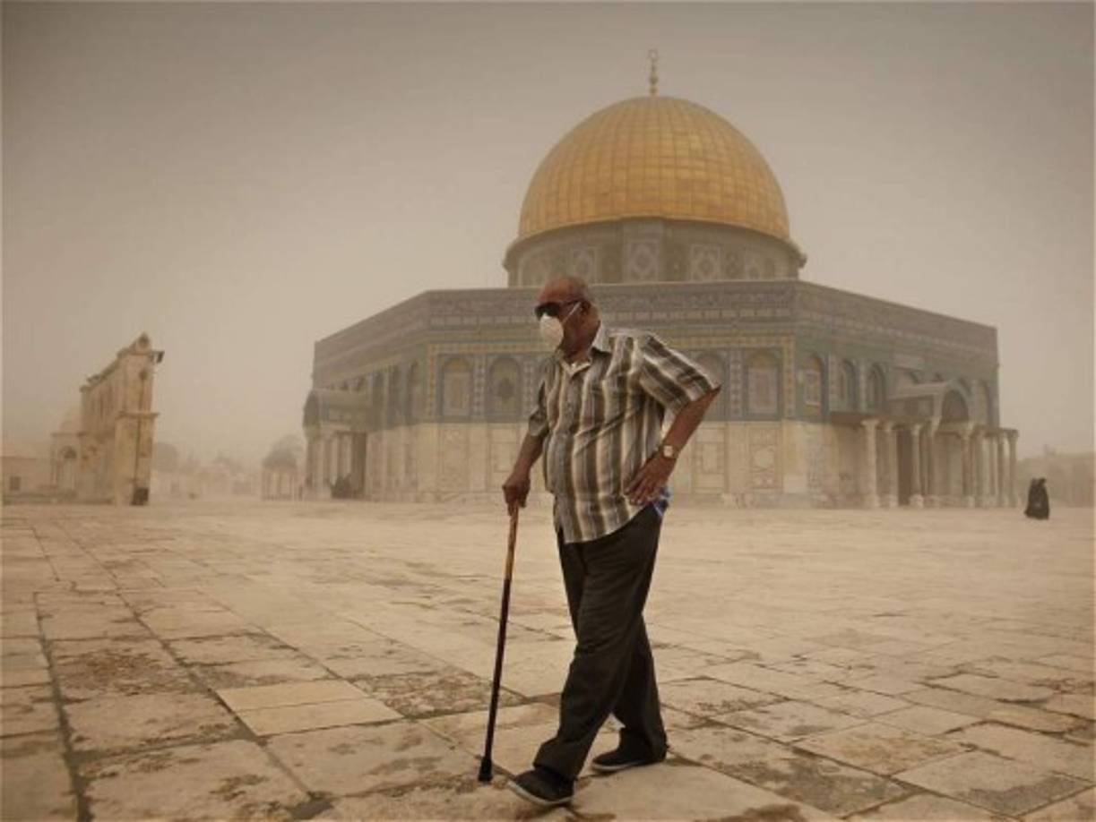 Un hombre camina bajo la tormenta de arena en cercanías al Domo de la Roca en Jerusalén.