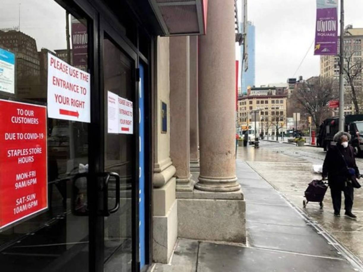 Una mujer camina frente a tiendas cerradas este jueves en el centro de Manhattan, Nueva York (EE.UU).