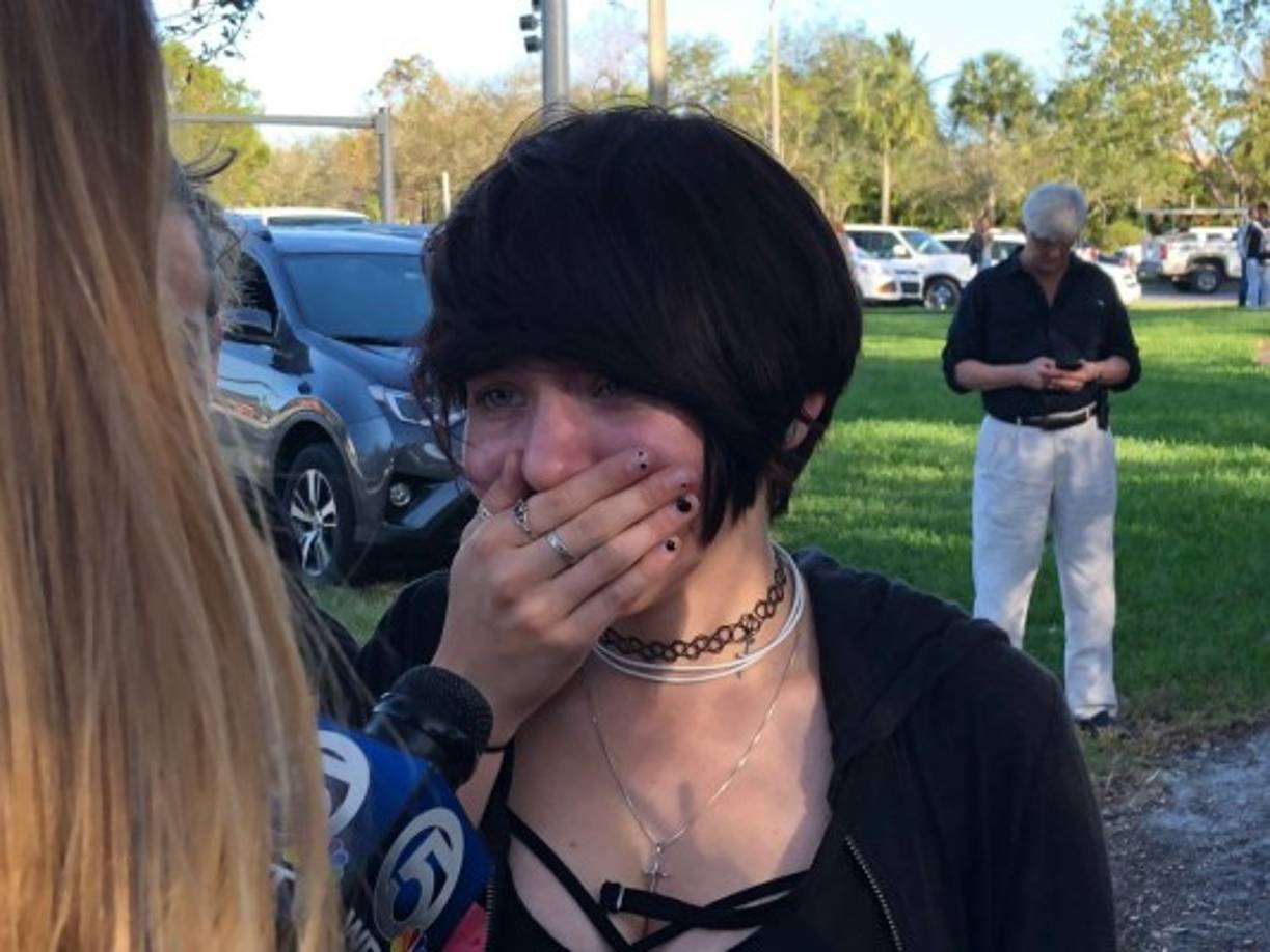 A student reacts as she talks to a television reporter at Marjory Stoneman Douglas High School in Parkland, Florida, a city about 50 miles (80 kilometers) north of Miami on February 14, 2018 following a school shooting.<br/>A gunman opened fire at the Florida high school, an incident that officials said caused 'numerous fatalities' and left terrified students huddled in their classrooms, texting friends and family for help.<br/>The Broward County Sheriff's Office said a suspect was in custody. / AFP PHOTO / Michele Eve SANDBERG