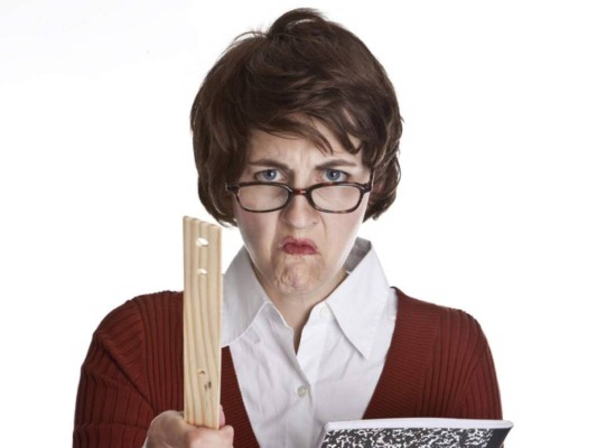 An angry teacher holding a composition book and pointing a ruler.