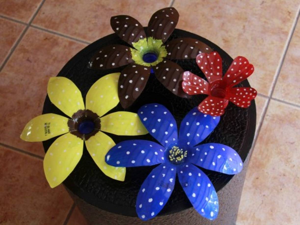Flores hechas con el plástico de las botellas de refresco. Utilice pintura acrílica y diseñe a su gusto.