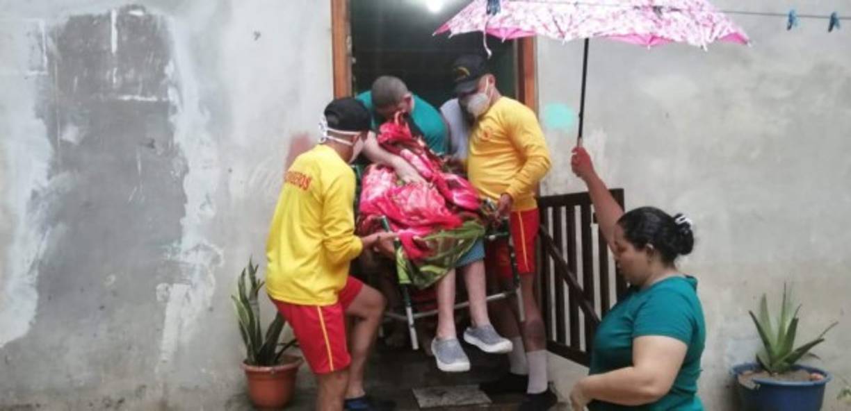 Los miembros del Cuerpo de Bomberos ayudan a una persona en silla a ser evacuada.