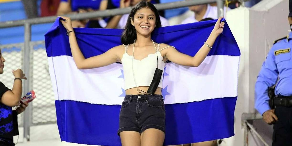 Una joven aficionada catracha, sonriente con la bandera de Honduras.