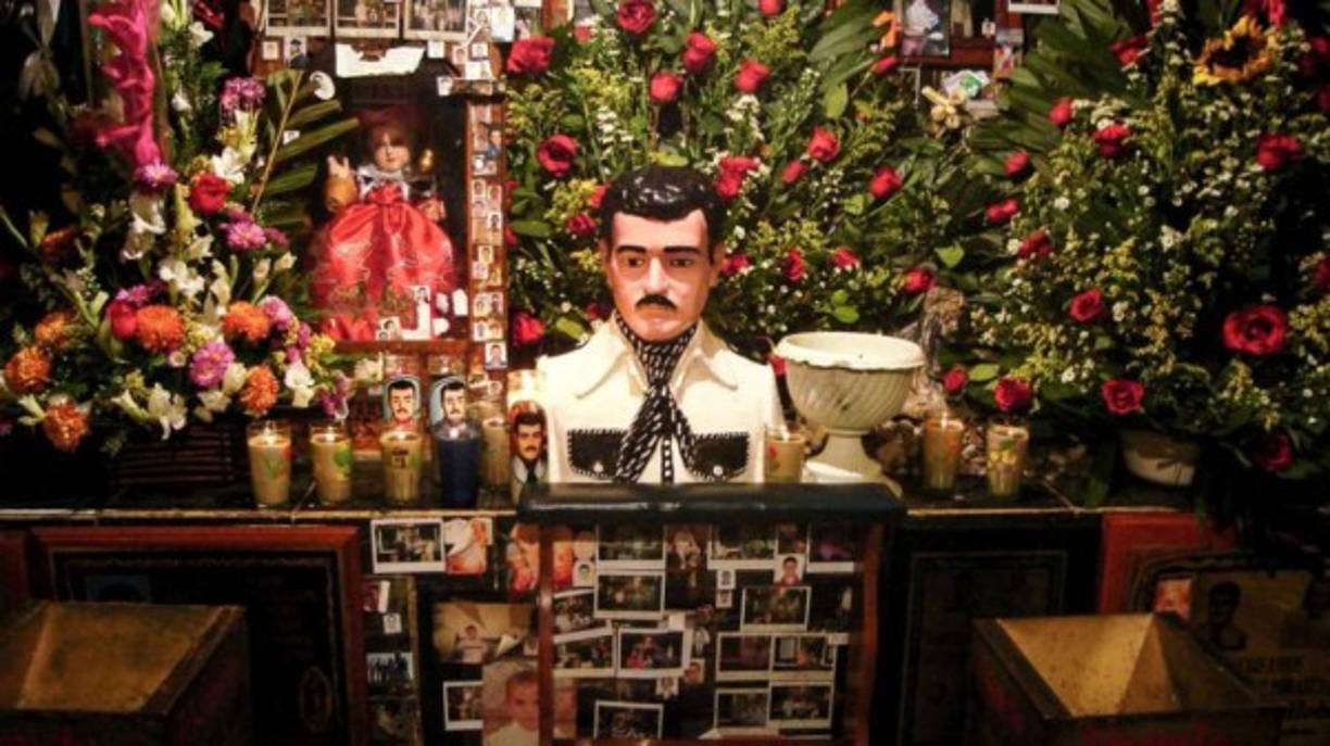 Malverde fue una especie de Robin Hood mexicano que se hizo de fama por asaltar a los hacendados de Sinaloa para repartir el motín entre las comunidades más pobres de la región.<br/><br/>Jesús murió en mayo de 1909, pero nació su mito y culto entre los mexicanos, que ahora lo veneran como un santo. <br/><br/><br/>Malverde, como se ha dicho, es conocido como 'El Santo de los Narcos'. Supuestamente, en los años 70, el capo Julio Escalante ordenó matar a su hijo Raymundo por realizar negocios sin su conocimiento. Según se afirma, herido de bala y arrojado al mar, Raymundo suplicó a Malverde su ayuda y fue entonces salvado por un pescador.