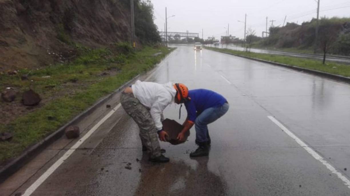 Trabajadores despejan una carretera que fue cubierta por los escombros provocados por un derrumbe.