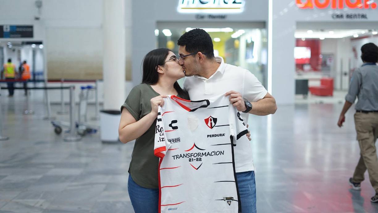 La pareja de hondureños se dio un beso mientras esperaban el arribo de la plantilla del Atlas.