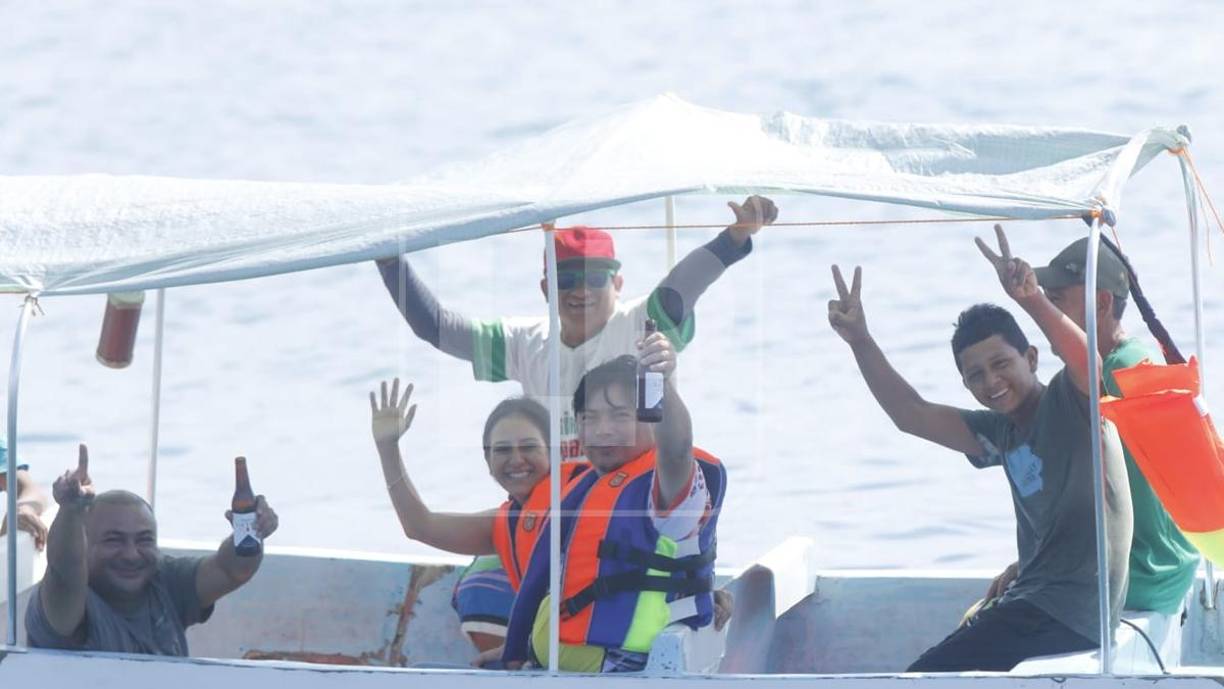 Un grupo de amigos saludan mientras abordan una lancha al dar un paseo por las playas de Tela.