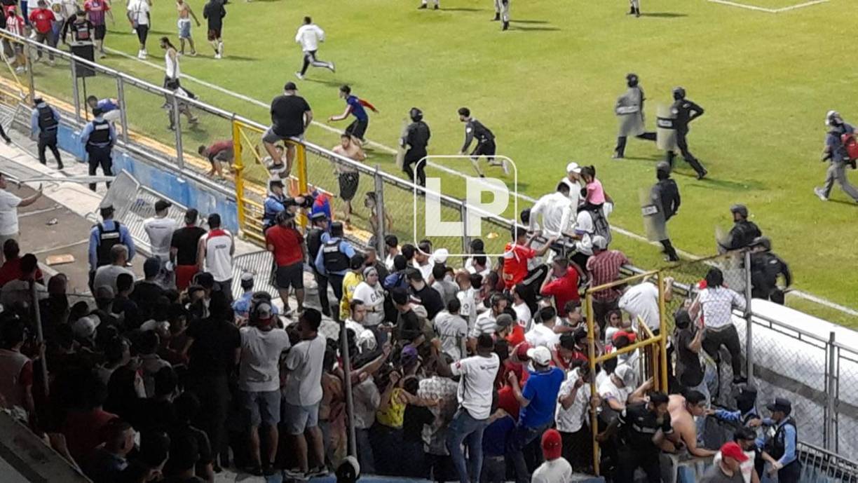 Aficionados del Olimpia invadieron el campo para buscar a hinchas del Motagua que se camuflajearon en las graderías del estadio Morazán.