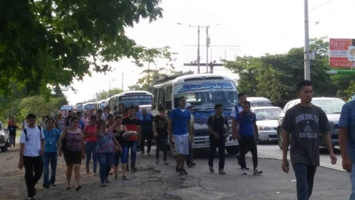 Pasajeros caminando debido al paro de transportistas.