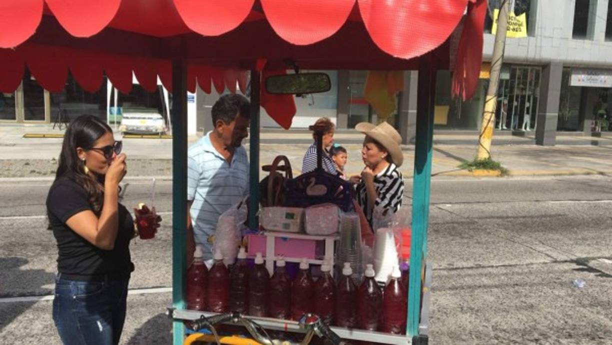 Mientras esperaban el colorido evento, algunos hondureños consumieron las bebidas y alimentos que en esta celebración aprovechan a vender humildes sampedranos.
