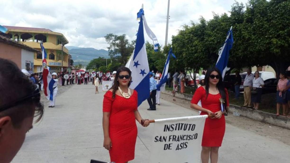 Dos jovencitas del instituto San Francisco de Asis de Ocotequepe, con lentes de sol, portan orgullosas la manta de su instituto.