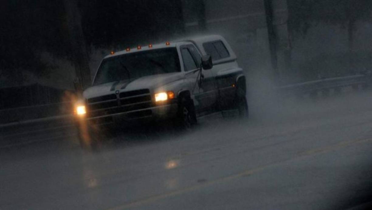 Vehículos recorren las inundadas calles de Cocoa Beach.
